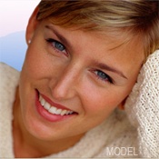 Close-up of smiling blond woman's face, who rests the side of her head on her hand.