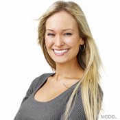 Grinning woman with long blonde hair and wearing a scoop-necked gray shirt.
