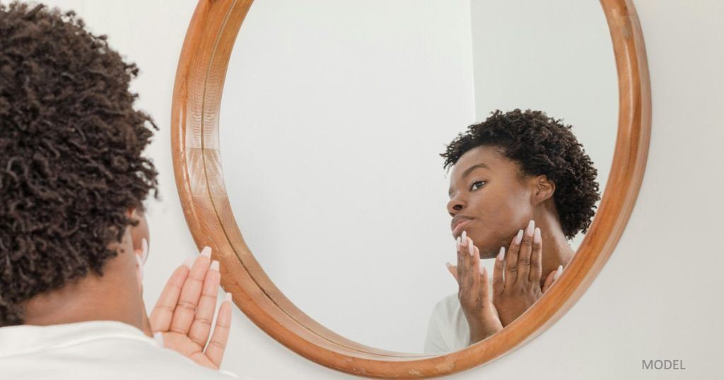 Antioxidants: Love Potions for Your Skin African-American woman looking at her skin in the mirror
