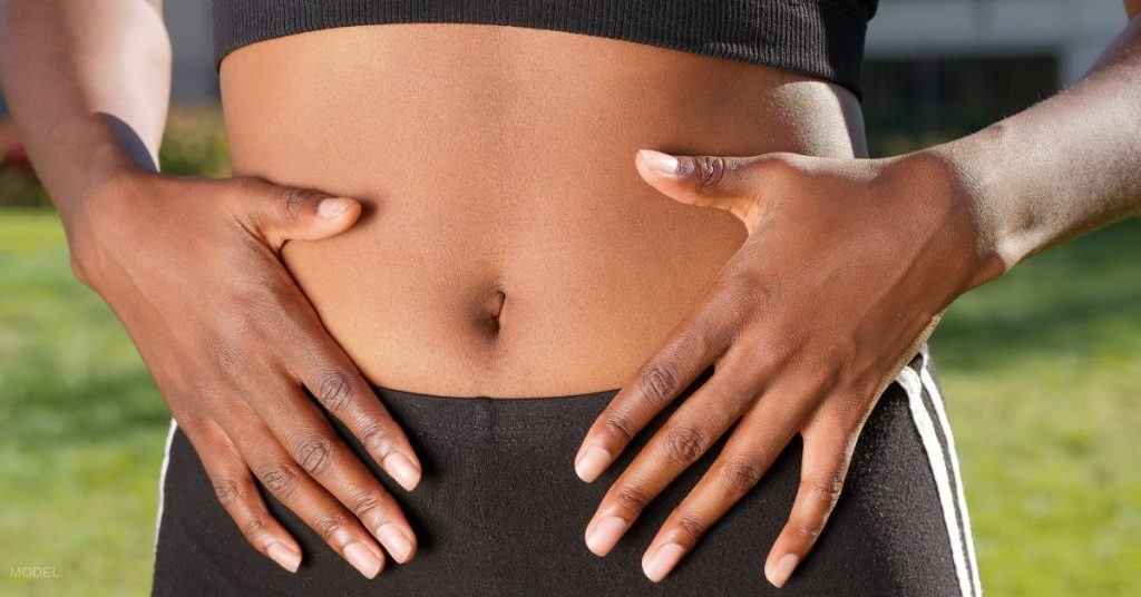 A woman holding her flat tummy. (Model)